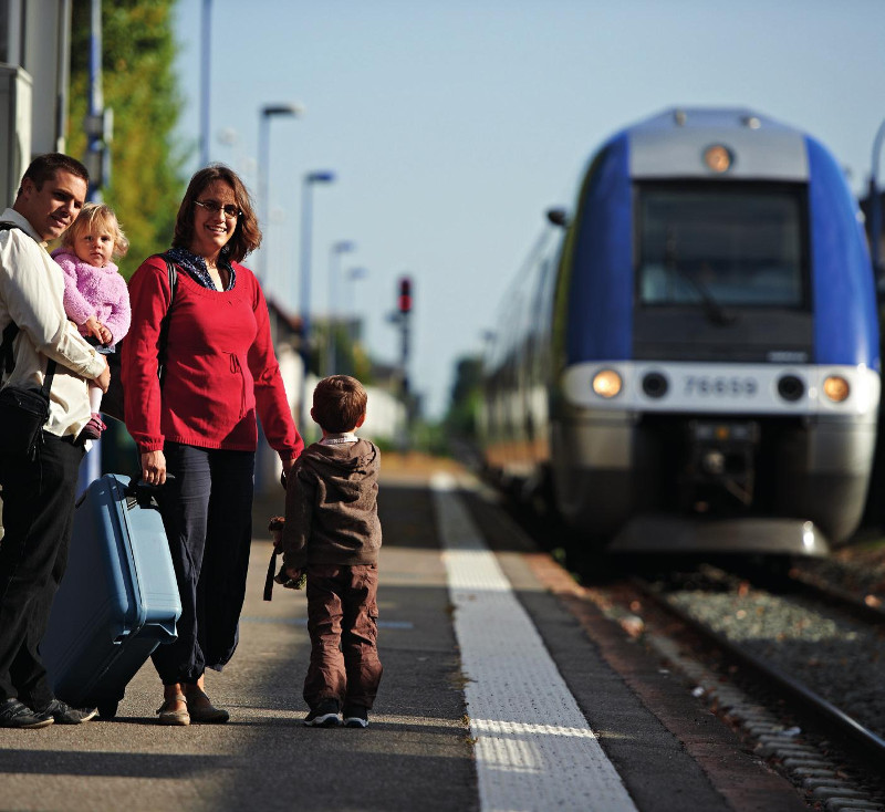 Famille de voyageurs attendant un TER sur un quai de gare